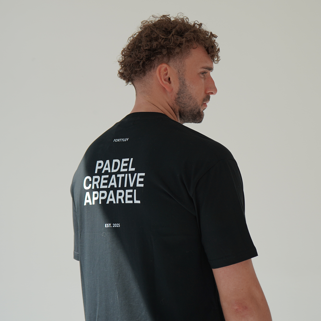 Man wearing a black t-shirt with 'PADEL CREATIVE APPAREL' text on the back against a plain background